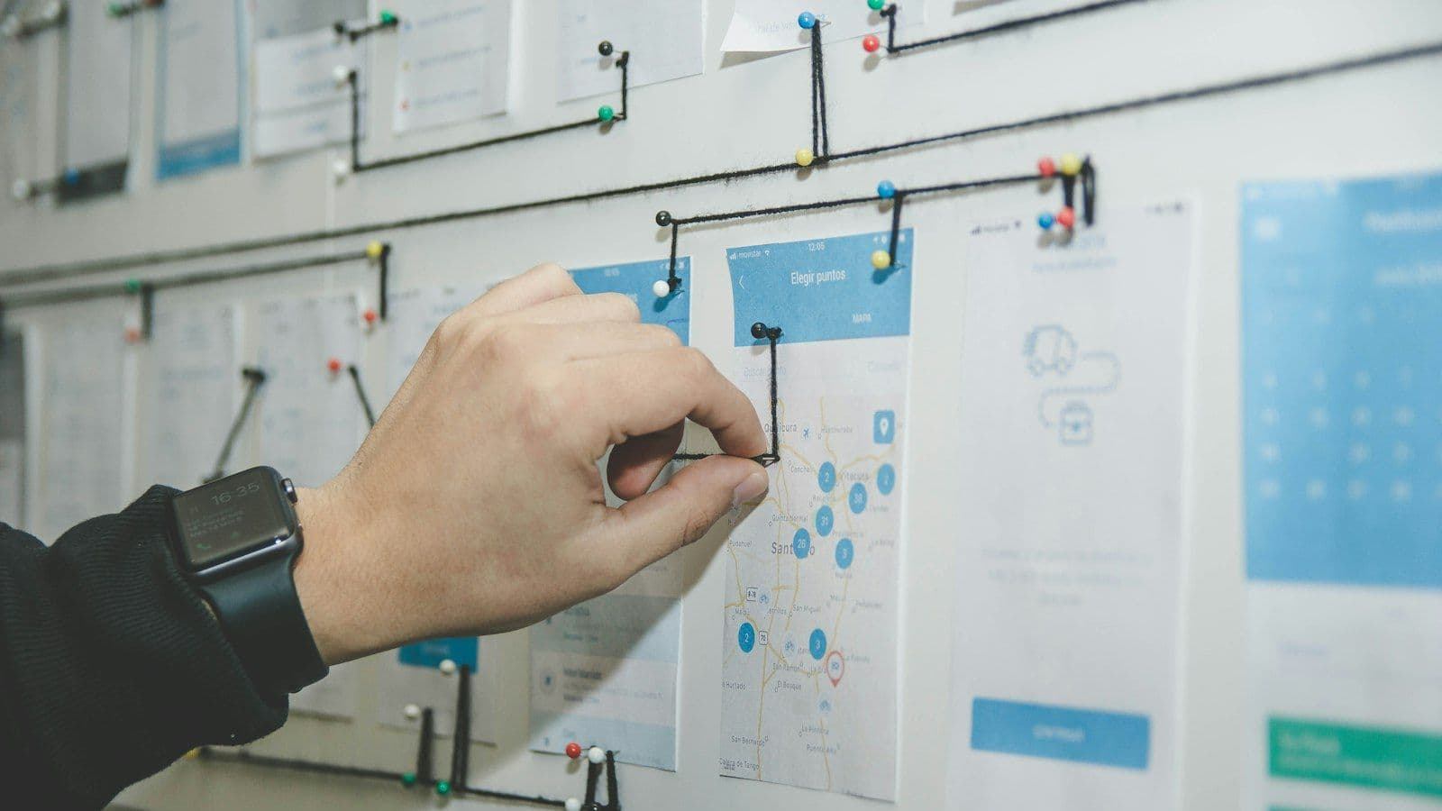 A wall of pinned interface screens connected with string.