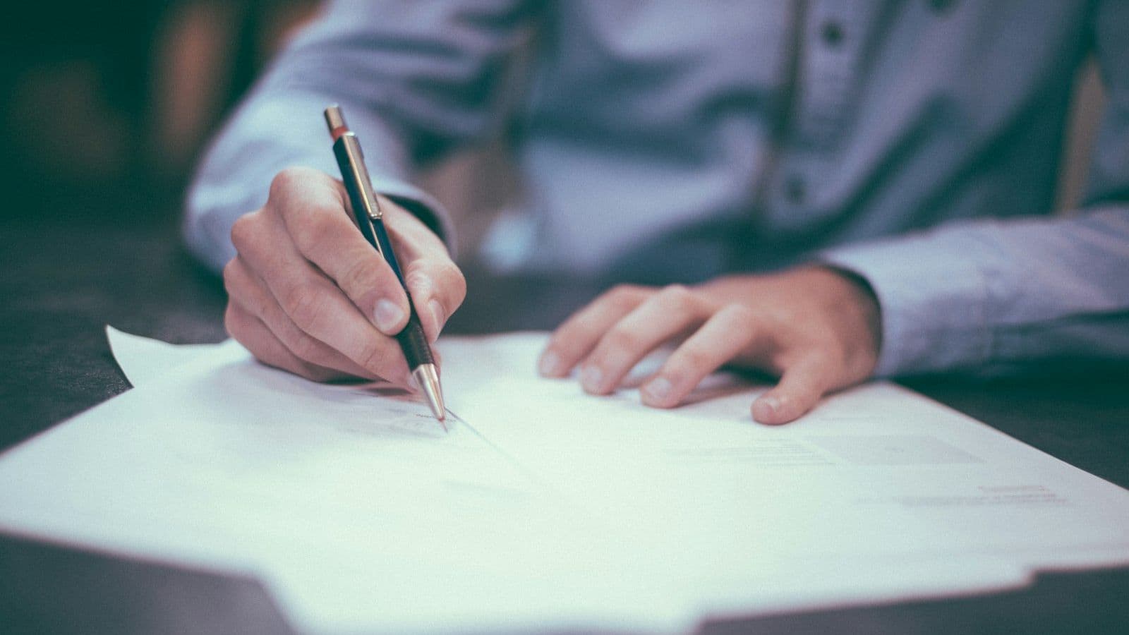 A person signing a written project plan at a desk.